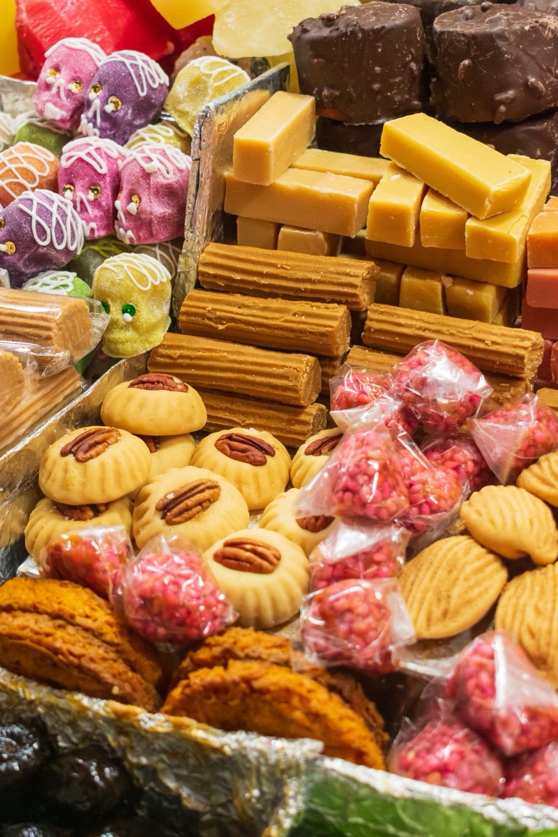 Una charola de dulces mexicanos tradicionales: cocadas, palanquetas, calaveritas de azúcar y dulce de tamarindo.
